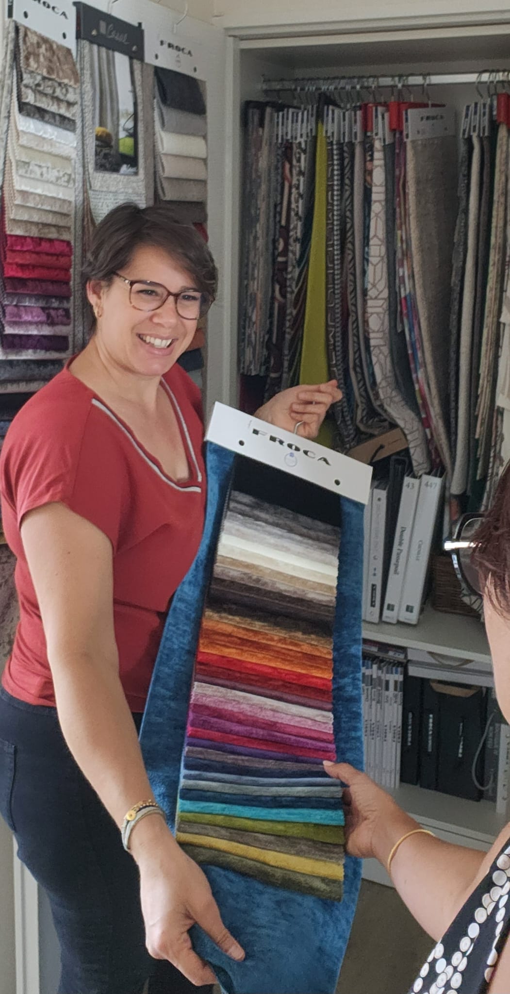 Artisan tapissière et commerciale à Nancy présentant des tissus à une cliente – Si j’avais un marteau